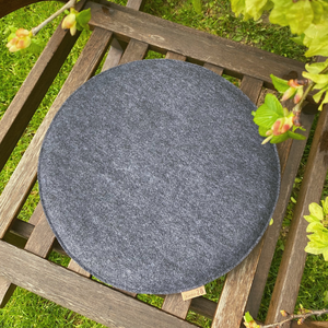 Stuhlkissen rund aus upcycling Filz auf einem Gartenstuhl aus Holz im Garten.