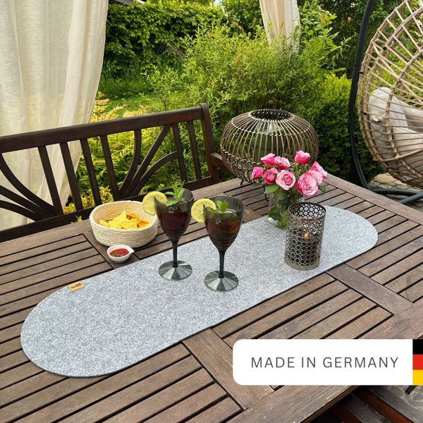 Tischläufer hellgrau aus Filz nachhaltig Made in Germany mit Rundung an beiden Seiten auf einem Holztisch im Garten