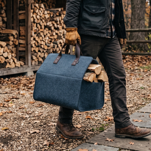 Blaue Filztasche für Kaminholz wird draußen getragen und ist mit Holzscheiten befüllt