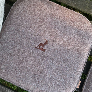 Filz Sitzkissen aus nachhaltigem Upcycling Filz in braun auf einer Holzbank mit dem Motiv Steinbock