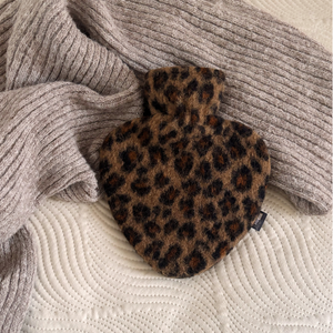 Herzförmige Wärmflasche mit Schurwollbezug im Leopardenmuster auf weicher Strickdecke