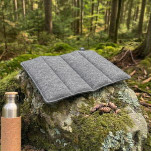 outdoor sitzkissen faltbar auf einem stein in wald für gemütliches sitzen beim wandern, im stadion, im konzert und beim campen