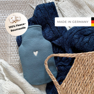 Kleine Wärmflasche mit Bezug aus kuscheliger Baumwolle auf einer blauen Decke