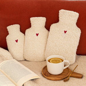 Kleine Wärmflaschen und Wärmflasche groß auf roter Couch